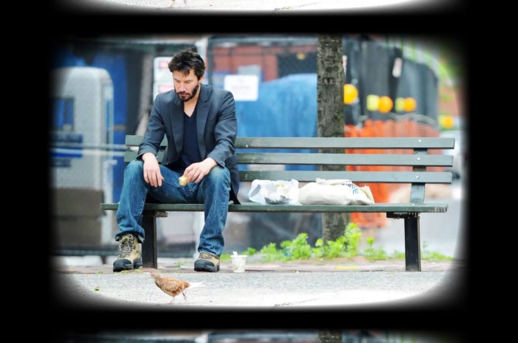 Keanu Reeves assit sur un banc